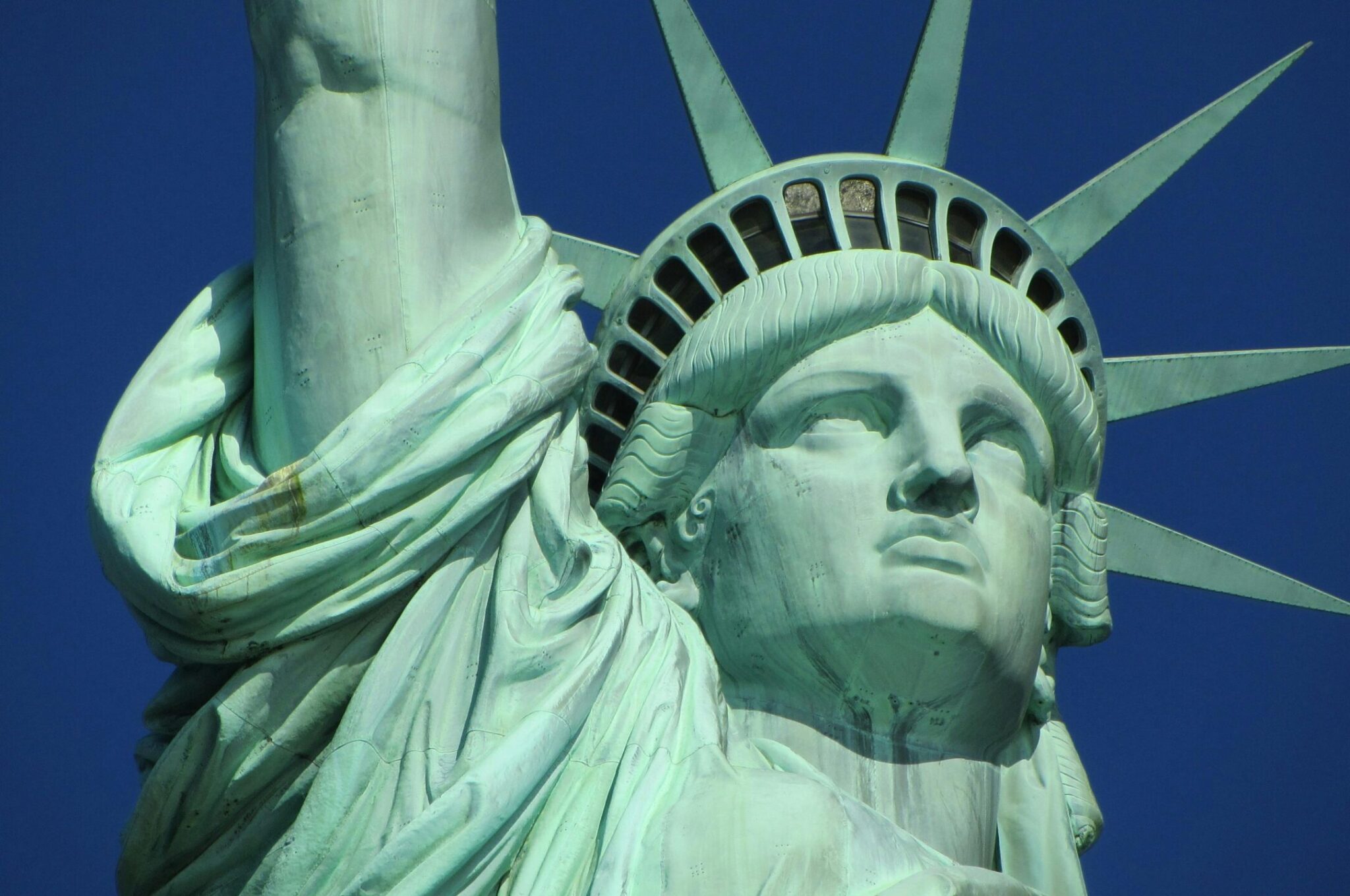 Detailed close-up of the Statue of Liberty against a clear blue sky.